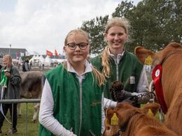 Glæde og stolthed lyser ud af disse to piger, der lige har fået en fløjplads med farmands ko med kalv.